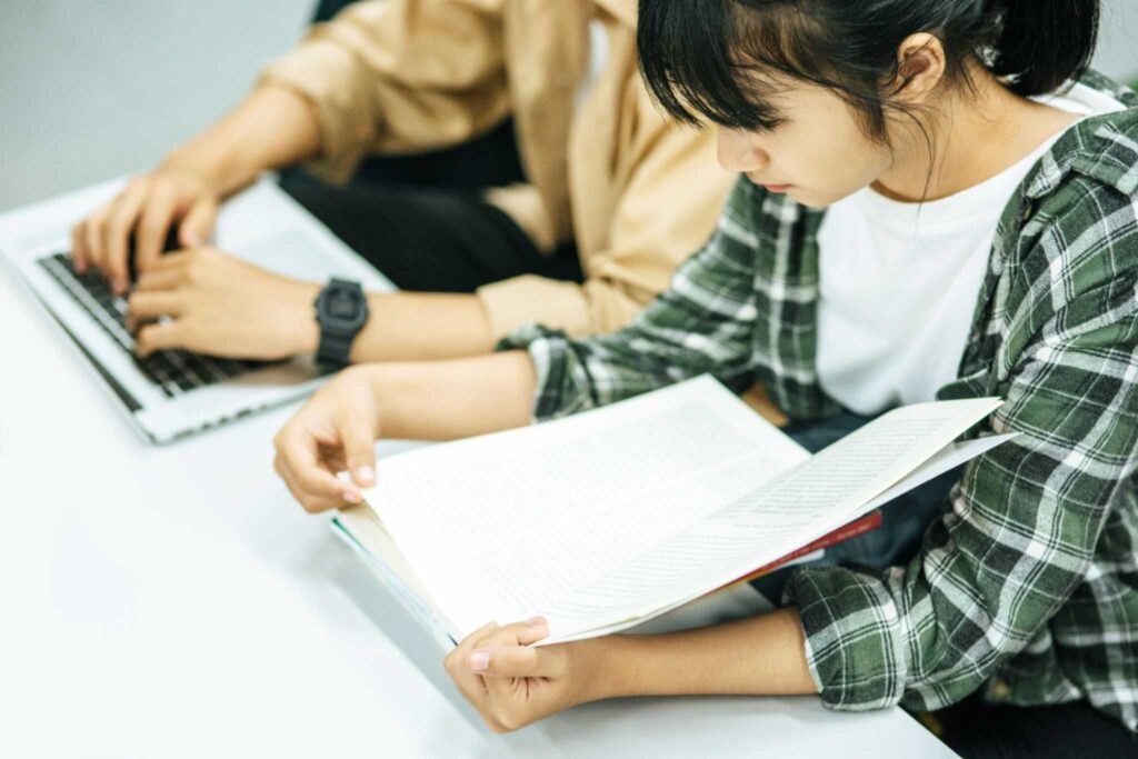 ผู้หญิงอ่านหนังสือและผู้ชายใช้แล็ปท็อปค้นหาหนังสือในห้องสมุด